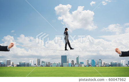 Business concept of risk support and assistance with man balancing on rope Business concept of risk support and assistance with man balancing on rope 60047982