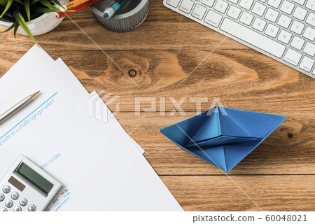 Office workspace with blue paper ship 60048021