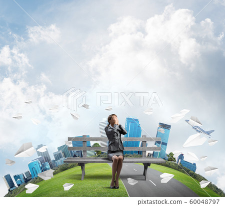 Young woman sitting on wooden bench outdoors Young woman sitting on wooden bench outdoors 60048797