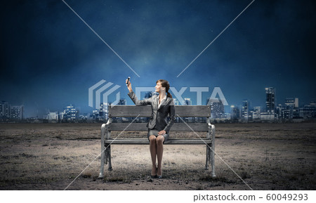 Business woman holding smartphone with raised hand Business woman holding smartphone with raised hand 60049293