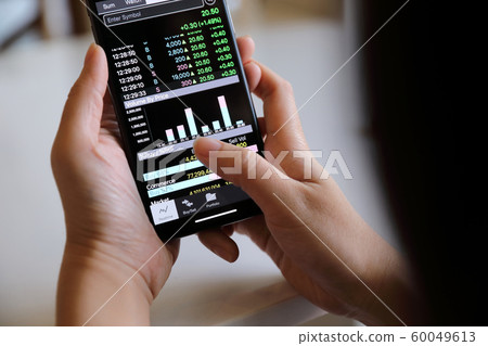 Female hand with smartphone trading stock online in coffee shop , Business concept 60049613