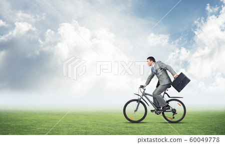 Young man riding bicycle on green grass Young man riding bicycle on green grass 60049778