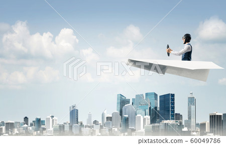 Businessman in aviator hat sitting in paper plane Businessman in aviator hat sitting in paper plane 60049786
