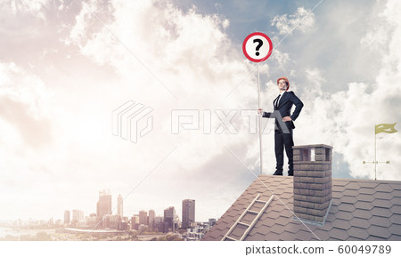Businessman on brick house roof showing banner with question mar Businessman on brick house roof showing banner with question mar 60049789
