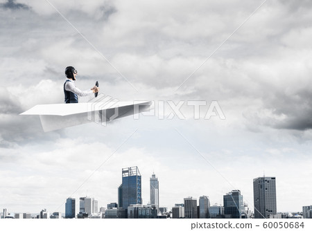 Aviator driving paper plane above business center Aviator driving paper plane above business center 60050684