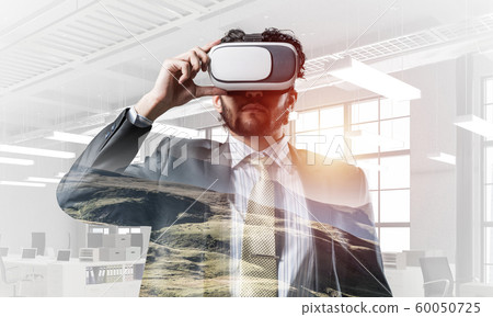Handsome elegant businessman experiencing impressive virtual reality. Mixed media Handsome elegant businessman experiencing impressive virtual reality. Mixed media 60050725