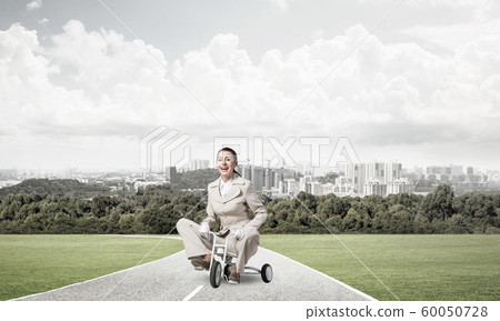 Beautiful happy woman riding children's bicycle 60050728