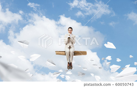 Beautiful young woman playing trumpet on book 60050743