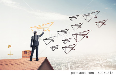 Businessman standing with back on house brick roof and drawing. 60050818