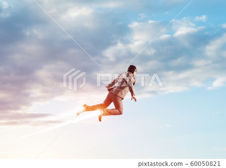 Businessman in suit and aviator hat flying in sky Businessman in suit and aviator hat flying in sky 60050821