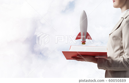 Woman showing rocket ship on open book 60050889