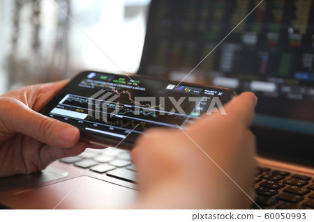 Female hand with smartphone trading stock online in coffee shop , Business concept Female hand with smartphone trading stock online in coffee shop , Business concept 60050993