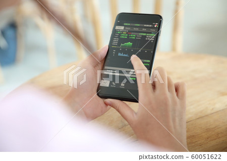 Female hand with smartphone trading stock online in coffee shop , Business concept Female hand with smartphone trading stock online in coffee shop , Business concept 60051622
