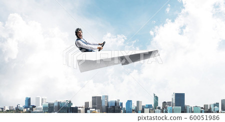 Aviator driving paper plane above business center Aviator driving paper plane above business center 60051986