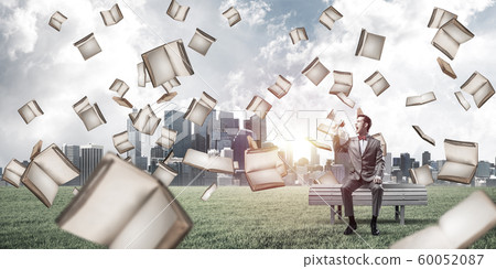 Businessman in summer park announcing something in loudspeaker and books falling from above Businessman in summer park announcing something in loudspeaker and books falling from above 60052087