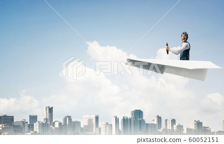 Aviator driving paper plane above business center Aviator driving paper plane above business center 60052151