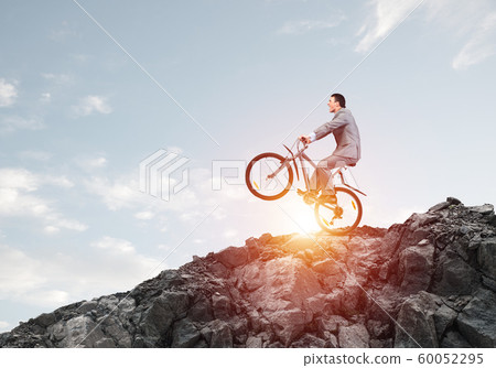 Businessman riding downhill by bike 60052295