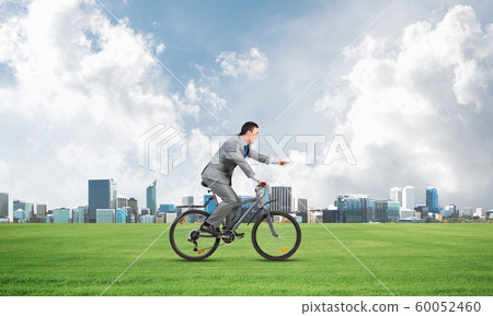 Businessman with paper documents in hand on bike Businessman with paper documents in hand on bike 60052460