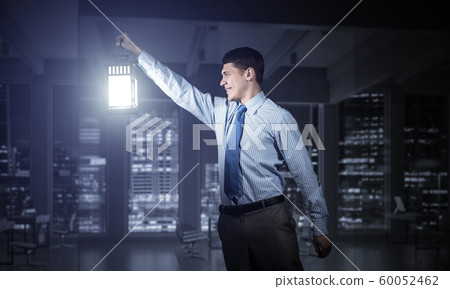Happy businessman holding glowing lantern Happy businessman holding glowing lantern 60052462