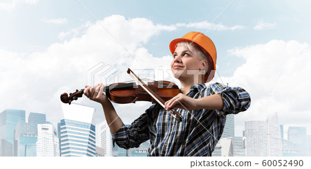 Beautiful woman in safety helmet playing violin 60052490
