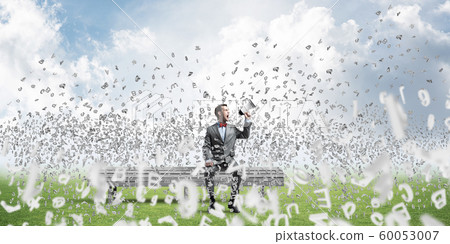 Businessman in summer park announcing something in loudspeaker and symbols fly around Businessman in summer park announcing something in loudspeaker and symbols fly around 60053007