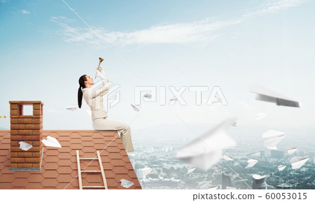 Beautiful young woman playing trumpet on roof 60053015