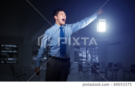 Screaming businessman holding glowing lantern 60053375