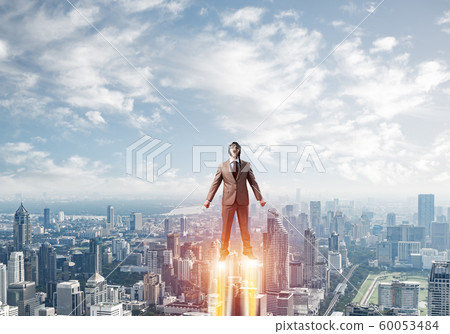 Businessman in suit and aviator hat flying in sky Businessman in suit and aviator hat flying in sky 60053484