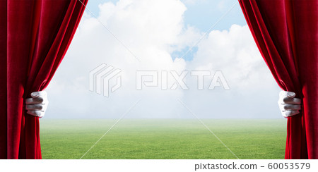 Green meadow behind red curtain and hand holding it Green meadow behind red curtain and hand holding it 60053579
