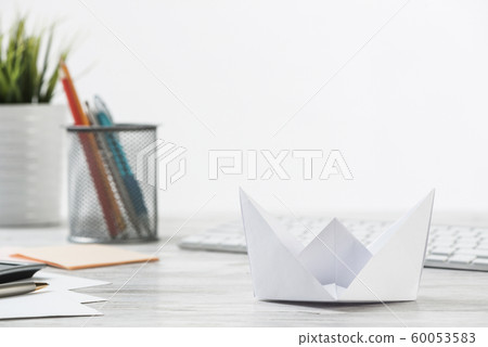 Wooden office desk with white origami boat. Wooden office desk with white origami boat. 60053583