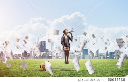 Young woman with megaphone sitting on lightbulb 60053586