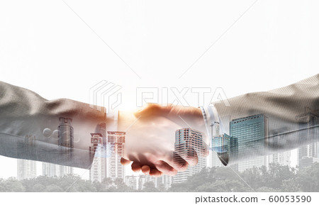 Business handshake as idea for unity and cooperation or greeting. Mixed media Business handshake as idea for unity and cooperation or greeting. Mixed media 60053590
