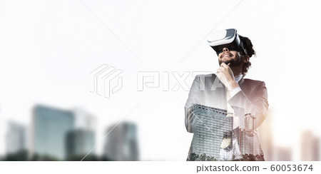 Handsome elegant businessman experiencing impressive virtual reality and business city at backdrop 60053674