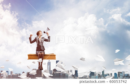 Young woman with megaphone sitting on big book 60053742