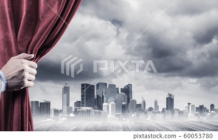Business city in gray fog behind red curtain and hand holding it Business city in gray fog behind red curtain and hand holding it 60053780