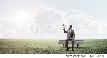 Businessman in summer park announcing something in loudspeaker Businessman in summer park announcing something in loudspeaker 60053791