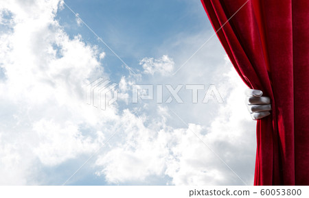 Cloudy landscape behind red curtain and hand holding it Cloudy landscape behind red curtain and hand holding it 60053800