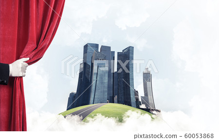 Modern cityscape behind drapery curtain and hand opening it 60053868