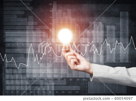 Businesswoman holding in hand glowing light bulb Businesswoman holding in hand glowing light bulb 60054097