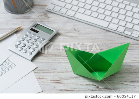 Top view office workspace with green paper ship Top view office workspace with green paper ship 60054117