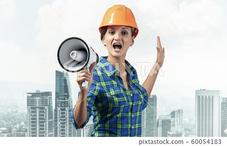Expressive woman in helmet shouting into megaphone 60054183