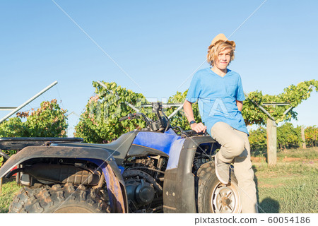 Young farmer standing near quad bike Young farmer standing near quad bike 60054186