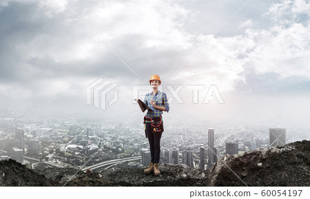 Young engineer in hardhat standing in front 60054197