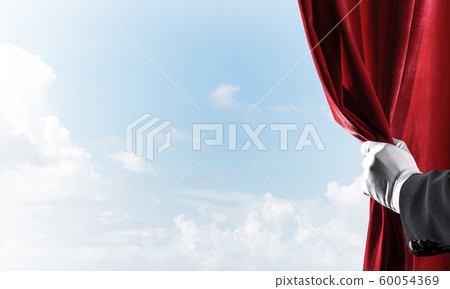 Cloudy landscape behind red curtain and hand holding it Cloudy landscape behind red curtain and hand holding it 60054369