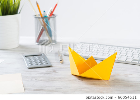 Workspace with office desk and yellow paper ship Workspace with office desk and yellow paper ship 60054511