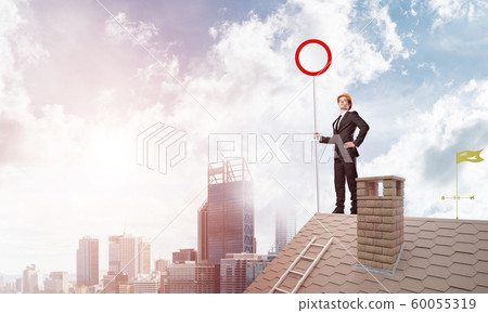 Caucasian businessman on brick house roof showing stop road sign. Mixed media 60055319
