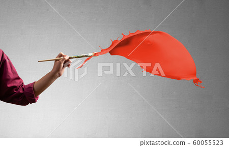 Close up artist hand painting red brush stroke 60055523