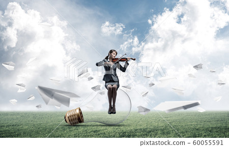 Young woman with violin sitting on glowing lamp Young woman with violin sitting on glowing lamp 60055591
