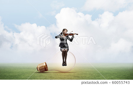 Young woman with violin sitting on glowing lamp Young woman with violin sitting on glowing lamp 60055743