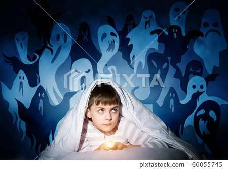Scared boy with flashlight hiding under blanket 60055745